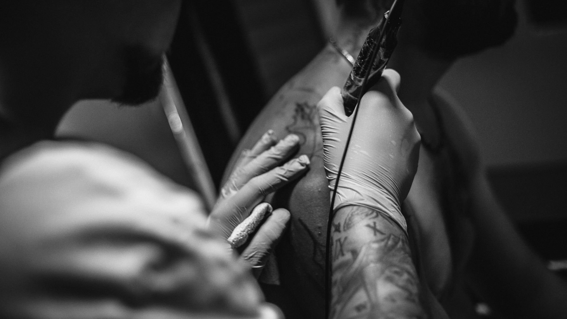 Tattoo artist in gloves creating detailed artwork on client's skin