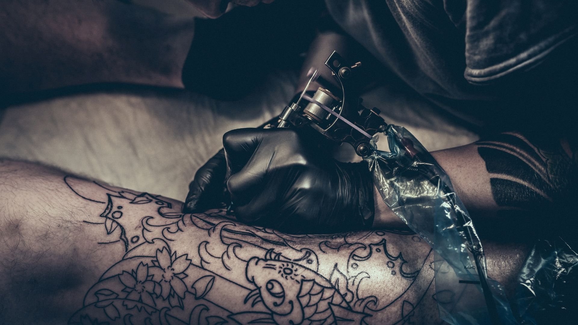 Tattoo artist in black gloves creating an intricate design on skin