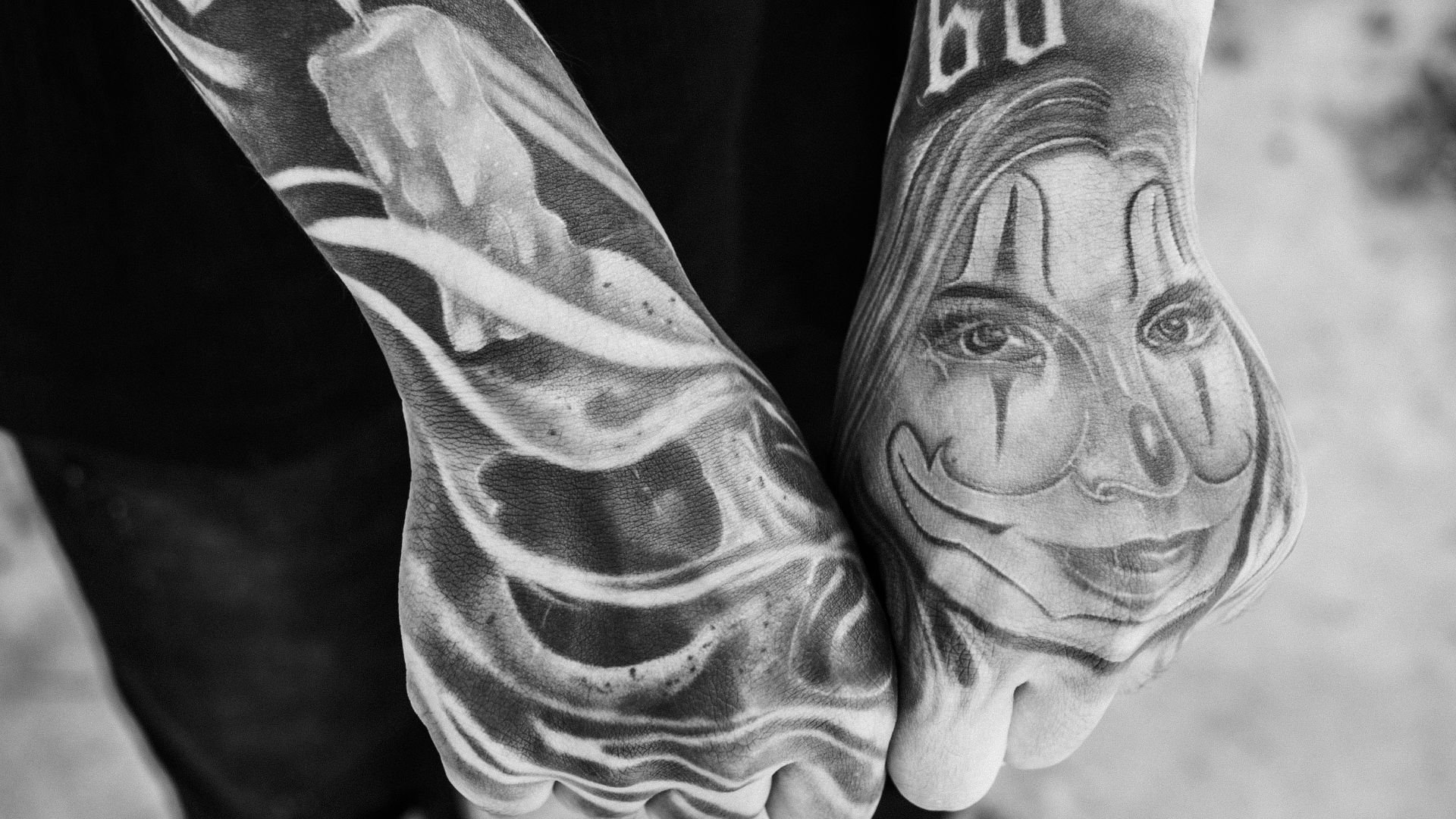Black and white detailed tattoos on two hands, abstract and portrait designs