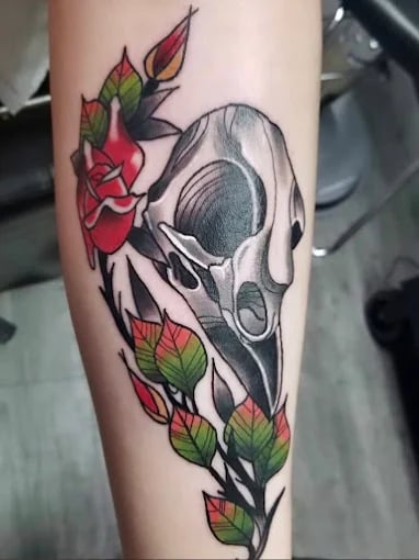Colorful tattoo of animal skull with red roses and green leaves
