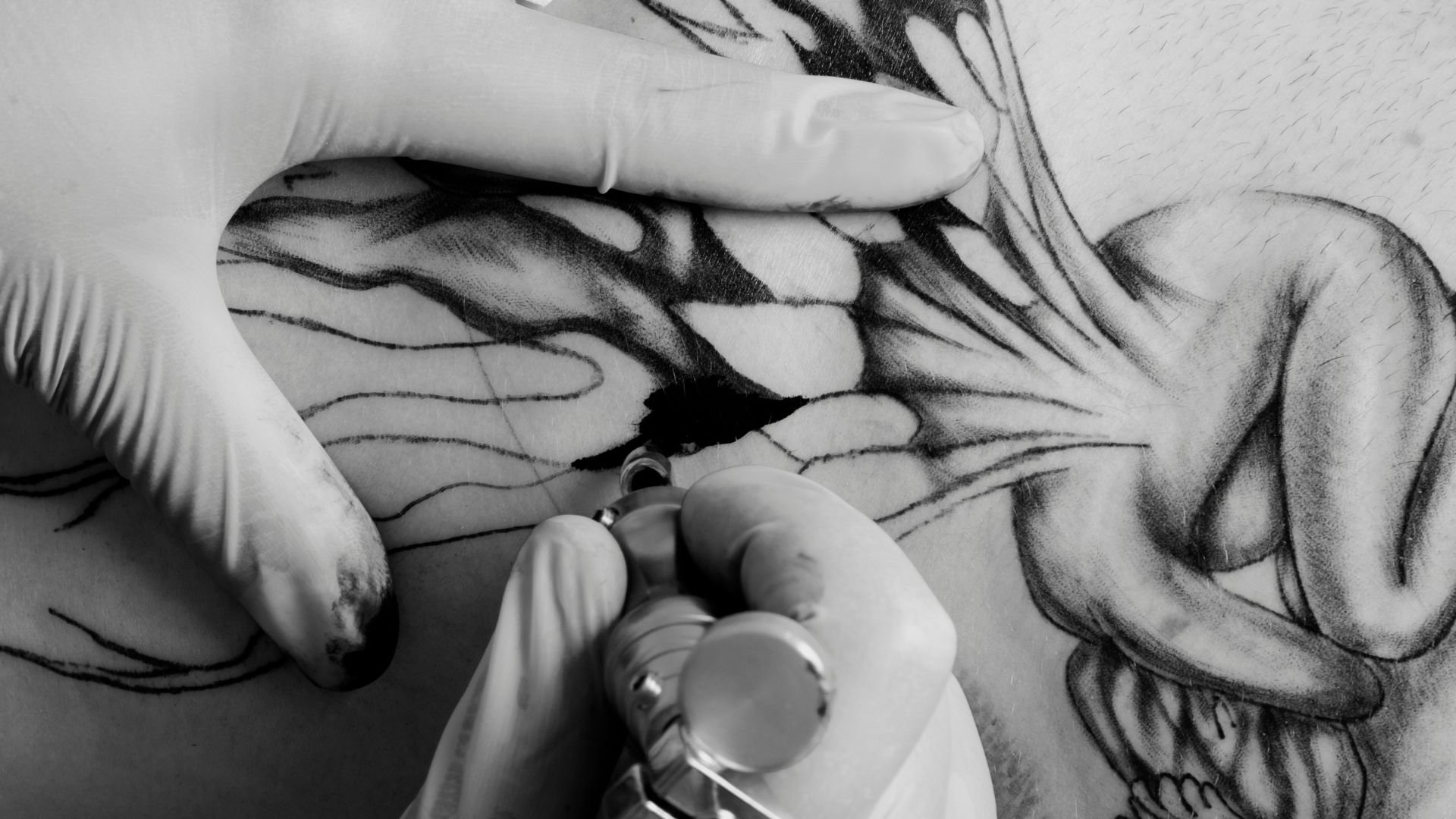 Tattoo artist creating intricate design on skin with tattoo machine