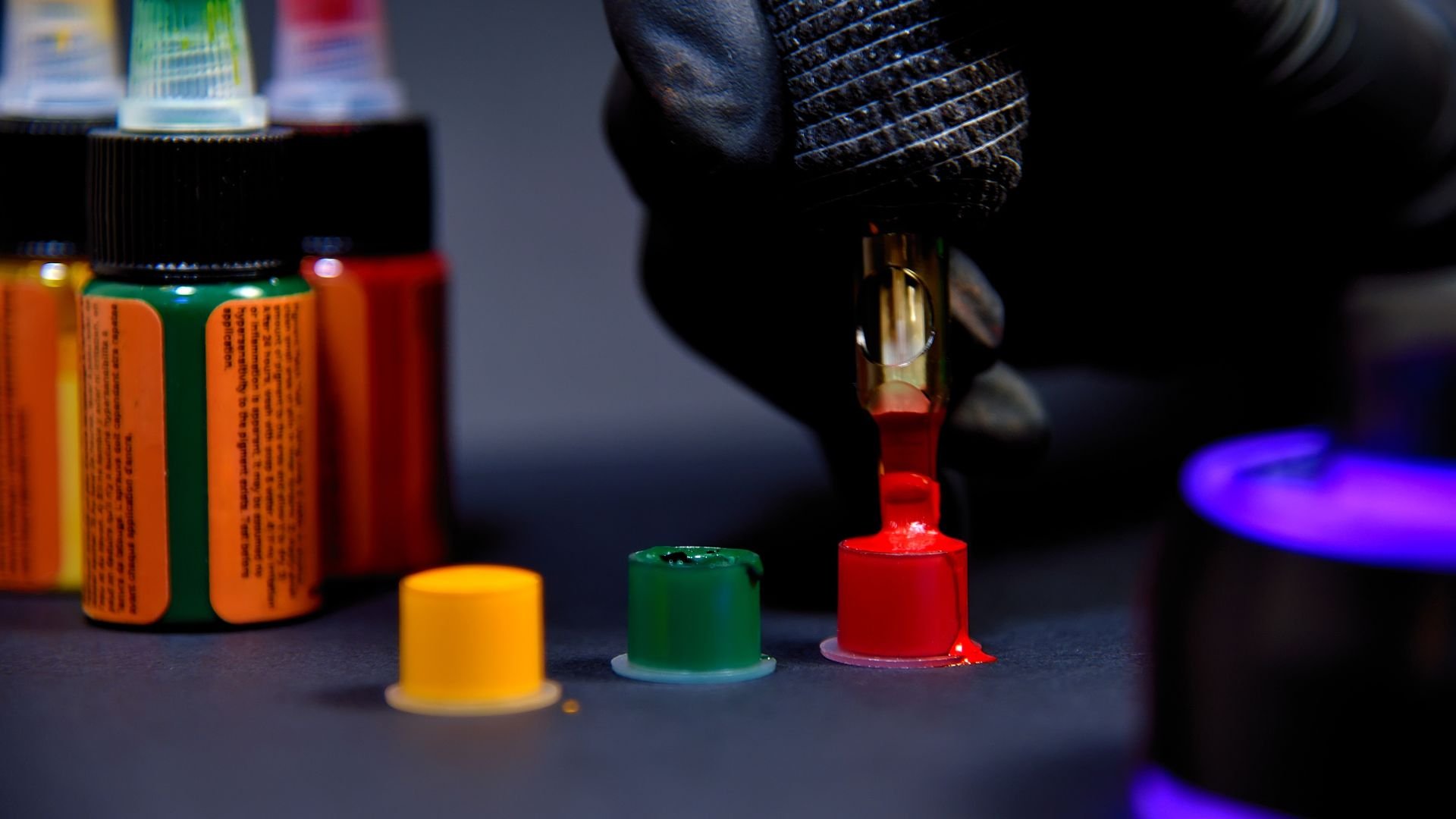 Colorful ink bottles and caps with a dropper on a dark background