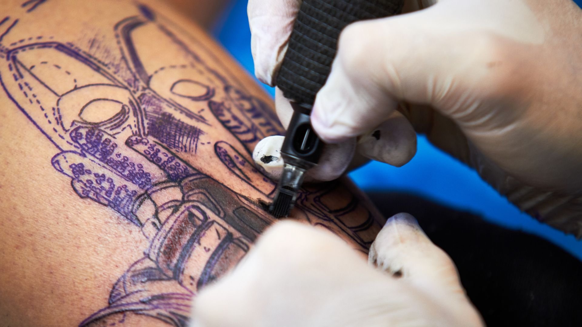 Tattoo artist creating detailed purple ink design on skin