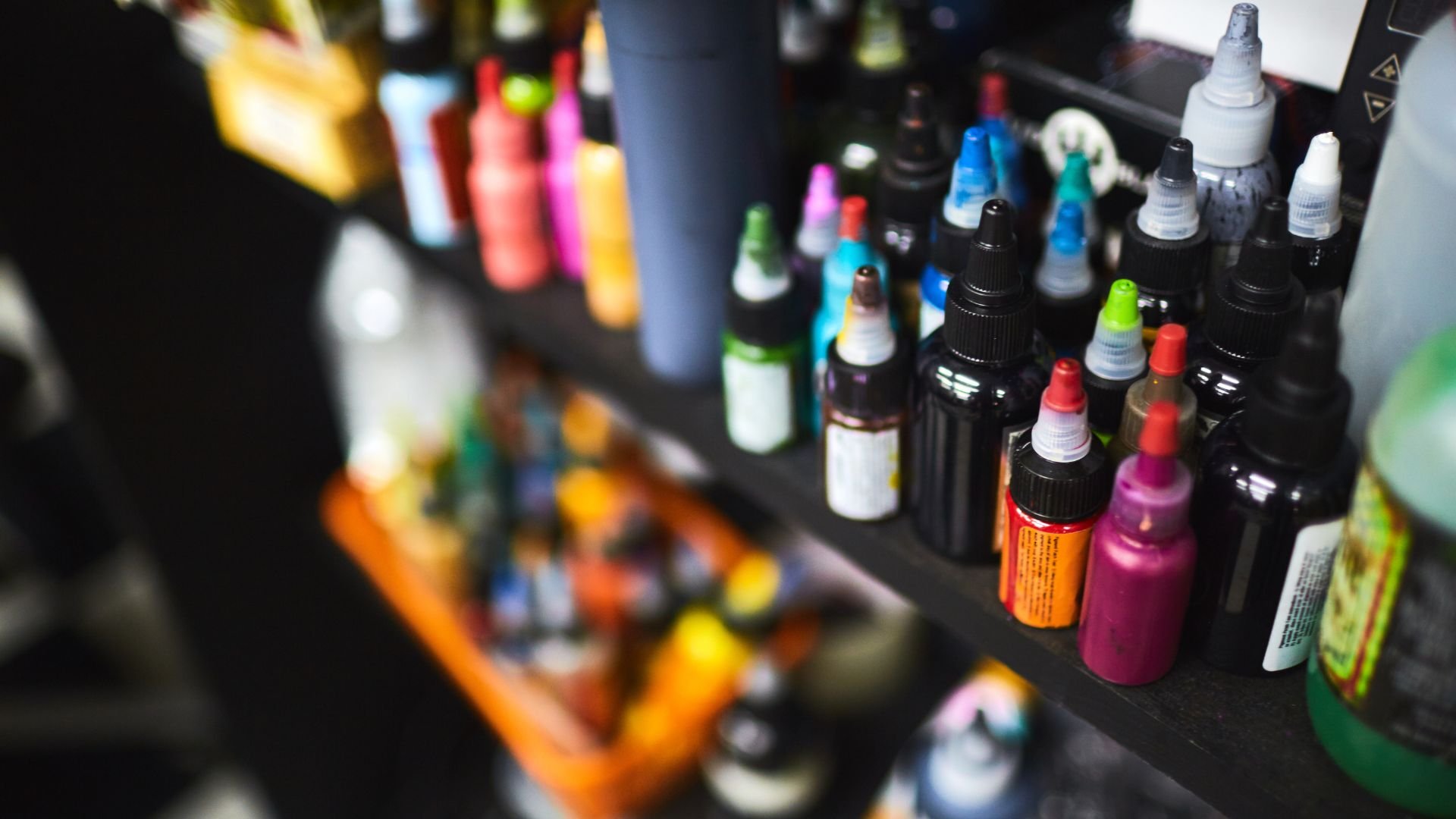 Colorful ink bottles lined up on shelves in a blurred background